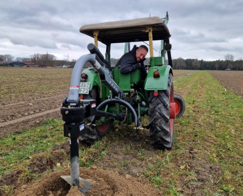Pflanzung April 2025: Traktor mit Erdbohrer in Aktion.